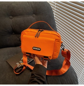 Detail of orange nylon messenger bag showing durable strap and MOONLEASA logo patch