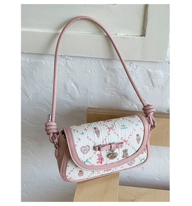 Close-up of white textured fabric with pink bow, bear print, and heart metal pendant