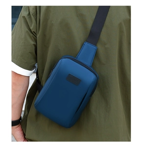 Rear view of model wearing a navy blue water-resistant crossbody bag with black leather logo