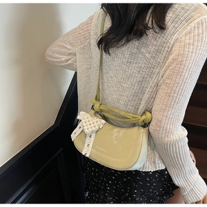 Detail of light green crescent shoulder bag with pearl bow and silver logo text
