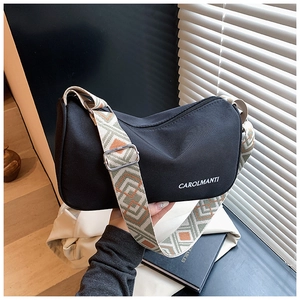 Détail du sac bandoulière en nylon noir avec sangle jacquard géométrique et logo de marque