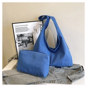 Detail of blue canvas hobo bag set with matching zipper pouch on denim jacket