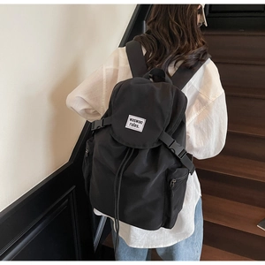 Back view of a black nylon backpack with waswac rules label on outdoor stairs