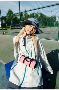 Close-up of pink cylinder running bag with grey windbreaker and blue sun hat