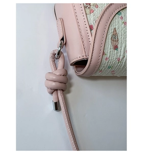 Close-up of pink crossbody bag with cartoon floral print and silver buckle detail
