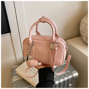 Pink matte bowling bag with heart charm and silver metal logo on silver suitcase background