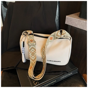 Détail du sac cylindrique crème avec bandoulière tissée et logo Carolmanti distinctif