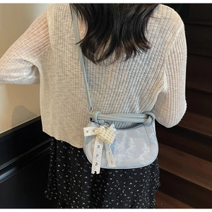 Close-up of light blue bag featuring unique cloud texture, pearl charm, and lace bow detail