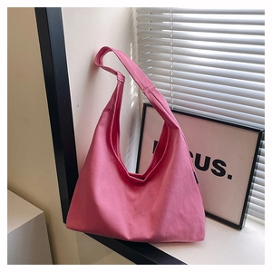 Pink canvas tote bag with wide shoulder strap displayed on a bright windowsill background