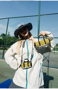 Close-up of mustard yellow nylon cylinder mini bag with black handles and adjustable lanyard