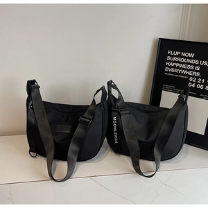 Detail view of two black nylon crescent hobo bags with adjustable shoulder straps