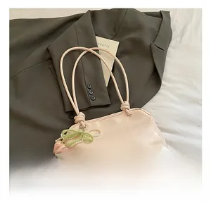 Dettaglio borsa tote rosa chiaro con spalline annodate, ciondolo a fiore e catena di perle