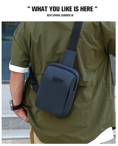Outdoor back view of a men's navy blue crossbody sport chest bag with adjustable strap