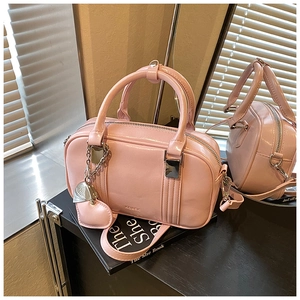 Detailed close-up of pink glossy Boston bag with silver hardware and heart charm decoration