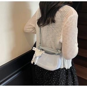 Detail of light blue crescent bag with pearl heart charm and lace bow on a shoulder strap