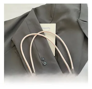 Dettaglio del manico rotondo con design a nodo su questa borsa a secchiello beige