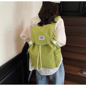 Detail view of the green nylon backpack with flap closure and adjustable white buckles