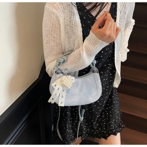 Detail of light blue crescent bag with white lace bow and pearl heart charm detail