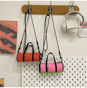 Vibrant orange and bright pink mini barrel bags hanging on a stylish wooden rack