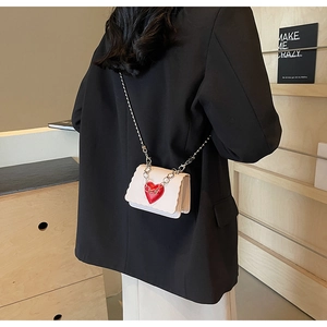 Close-up of white mini crossbody bag with red heart detail and silver chain strap