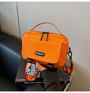 Detail of bright orange waterproof nylon messenger bag featuring logo and top handle