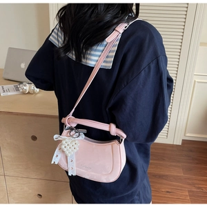 Detail of light pink crescent bag featuring a pearl heart charm and knotted strap detail