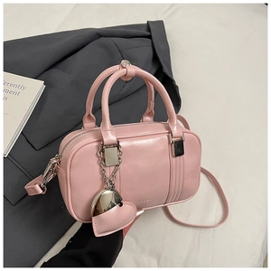 Close-up of pink Boston bag showing PU leather texture and silver heart pendant detail