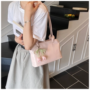 Detail of pink patent leather handbag with knot shoulder strap and tulip pearl charm