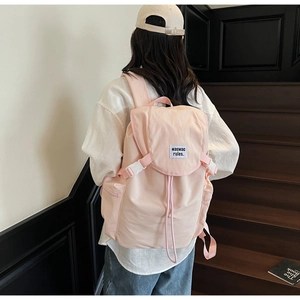 Detail of light pink canvas backpack featuring flap buckle closure and woven label