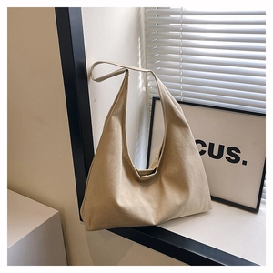 Detailed texture of khaki canvas tote bag with wide strap against shadow backdrops