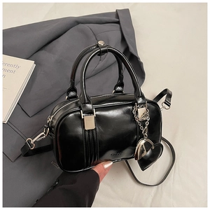 Close-up of black glossy Boston bag with heart charm and KOGOR embossed logo