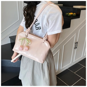Detail of light pink patent leather tote bag featuring tulip and pearl bow charms