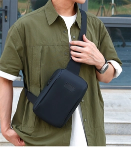 Outdoor shot showing detail of the black sport crossbody bag with embossed logo