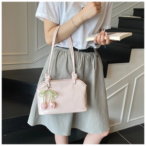 Detail of light pink shoulder bag with knot handle, pearl bow and tulip pendant charm