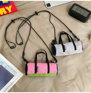 Detail view of two cylindrical mini crossbody sports bags with adjustable rope straps