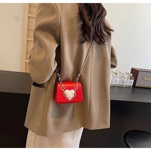 Detail of red mini crossbody bag with heart buckle and silver bead chain strap