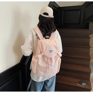 Close-up of pink nylon backpack featuring side zipper pocket and drawstring closure design