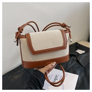 Close-up of canvas and brown leather stitching on a minimalist crossbody bag with brand logo