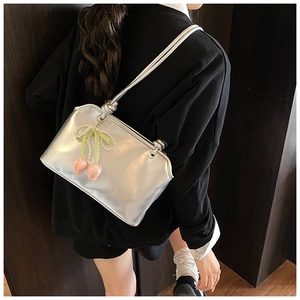 Detail of silver metallic shoulder bag with pearl bow and pink tulip charms on black shirt