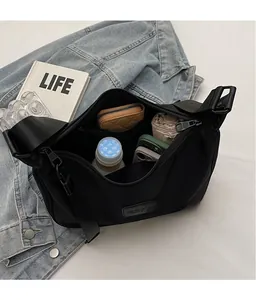 Macro shot showing large storage capacity of a black nylon crossbody bag with daily items