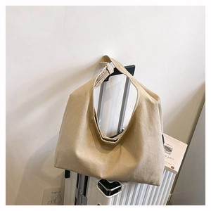 Large beige canvas tote bag mounted on a white suitcase handle for travel and commute