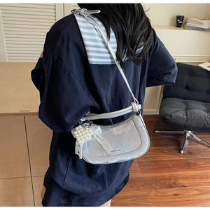 Silver shoulder bag detail with pearl heart charm and lace bow on a female model