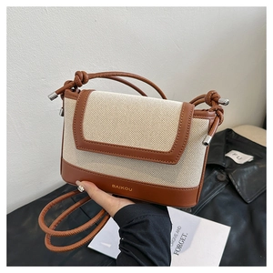 Detail of canvas crossbody bag with brown leather trim and knotted shoulder strap