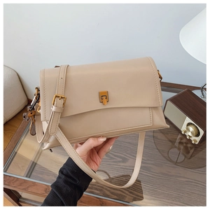 Détail du sac beige en similicuir avec fermoir rotatif doré et pendentif ours décoratif