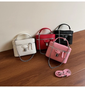 Detail view of four textured leather crossbody bags with metal chains and padlocks