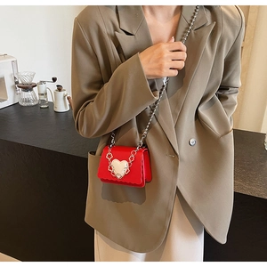 Mini red crossbody bag with silver heart buckle and chain strap shown on person