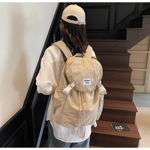Detail of the drawstring closure and secure plastic buckle on this beige canvas backpack