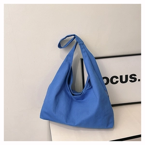 Detailed texture of blue canvas tote bag with wide shoulder strap and brand label