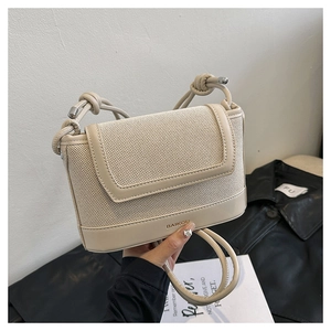 Close-up of structured cream shoulder bag featuring woven texture and knot strap detail