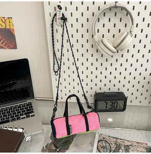 Detail of pink knitted mini crossbody bag with adjustable strap on white pegboard